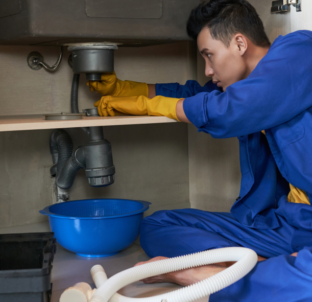 asian-plumber-blue-overalls-clearing-blockage-drain 1